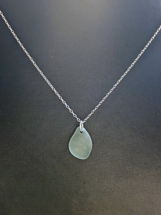 Necklace with a teardrop-shaped sea glass pendant on a dark background