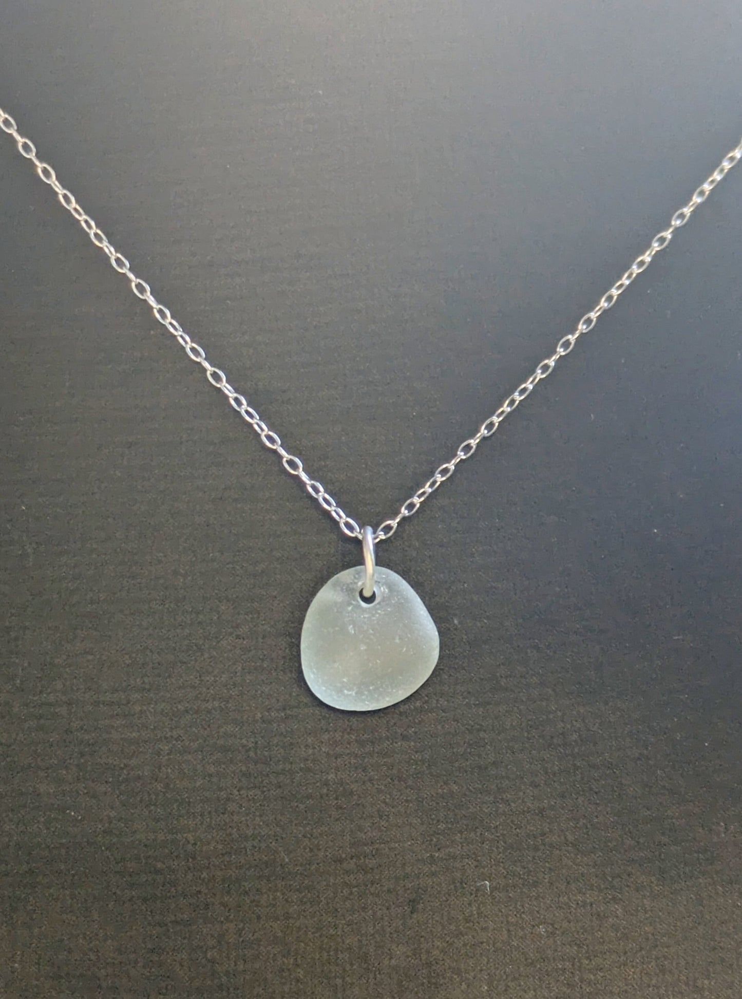 Necklace with a round sea glass pendant on a dark background